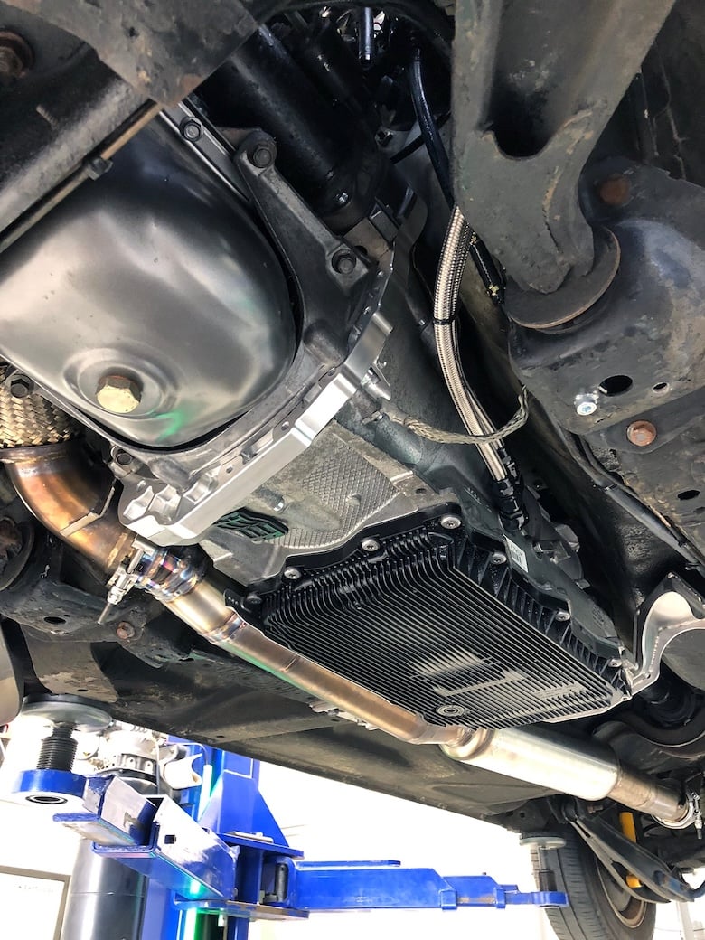 Close-up beneath the Volvo 240 showing the installed ZF 8HP transmission beside the modified exhaust.